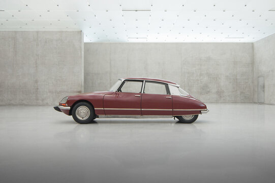 Maroon Citro&euml;n DS in big pavilion with grey concrete walls. Side profile view of old 1970s executive Citro&euml;n sedan. Bregenz, Austria - August 01 2013.