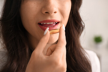 Beautiful young happy woman with healthy fish oil capsule at home, closeup