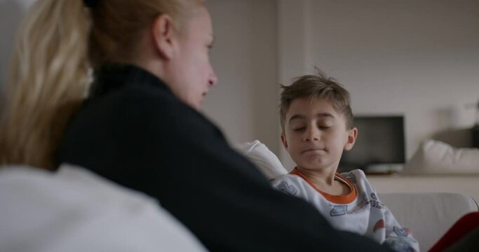 A mother is seen berating her young son, who appears attentive and possibly remorseful, in the familiar environment of their home.