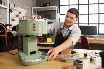 Male worker repairing coffee machine in workshop