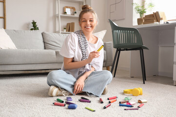 Young woman sitting on floor with different disposable electronic cigarettes at home