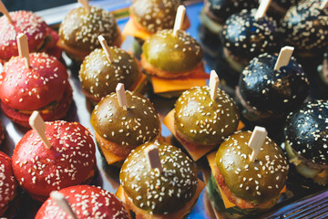 Burger mini burgers, snacks on a wooden table with craft paper, beautifully decorated catering banquet table on corporate christmas birthday party event or wedding celebration with colored burgers