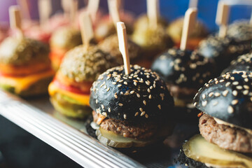 Burger mini burgers, snacks on a wooden table with craft paper, beautifully decorated catering banquet table on corporate christmas birthday party event or wedding celebration with colored burgers