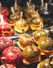 Burger mini burgers, snacks on a wooden table with craft paper, beautifully decorated catering banquet table on corporate christmas birthday party event or wedding celebration with colored burgers