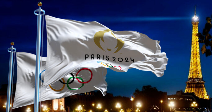 Paris 2024 Olympic flag waving with blurred Paris skyline at night.