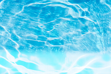Blue water with ripples on the surface. Defocus blurred transparent blue colored clear calm water surface texture with splashes and bubbles. Water waves with shining pattern texture background.