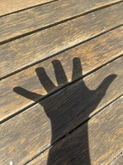 Shadow of a hand on wooden deck