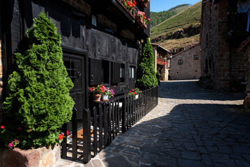 Small medieval village with cobblestone streets and a stone building with a black fence with potted...