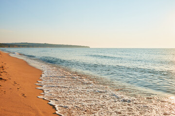 Tranquil Seashore with Footprints in Sand. This serene beach scene features gentle waves lapping against the shore, leaving behind a trail of footprints in the soft sand.
