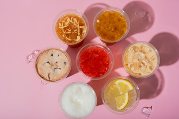 Colourful summer drinks with ice top view. Lemonades and coctails on pink background