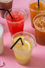 Colourful lemonades and coctails angle view. Takeaway glasses of summer drinks with ice close up.