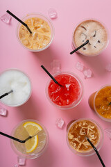 Colourful summer alcoholic cocktails and ice cubes on pink background top view