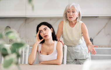 Elderly woman during family quarrel with young woman in kitchen at home