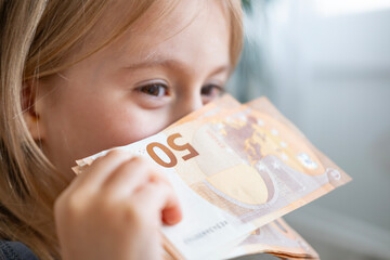 female child, cheerful girl holds 50 euro banknotes close-up, imagination ignited power money,...