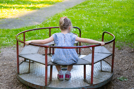 happy preschool girl, child spinning on carousel on summer day, dizziness and balance, joyful Carefree childhood memories, vestibular apparatus training