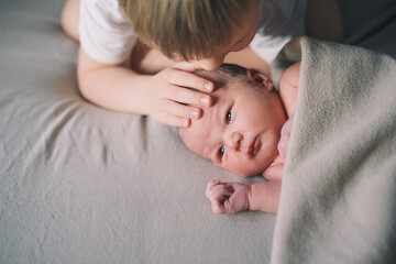 Siblings bonding. A boy and his little new born brother. Child and newborn baby at home. Concept of family with kids.