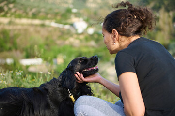 Affectionate young woman embracing pet dog in the nature. Happy female enjoying spending time with her cocker spaniel outdoors