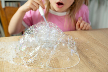 child experiments with blowing soap bubbles, Young Girl Performing Fascinating Science Experiment...