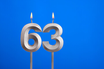 Birthday number 63 - Candle lit on blue background