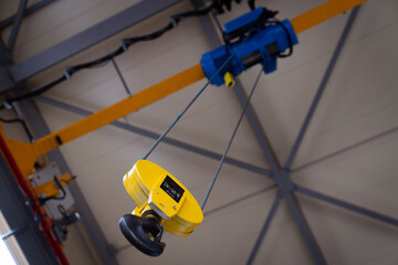 Overhead traveling cathead with steel hooks in industrial industrial warehouse. Steel slings.