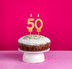 Birthday cake with number 50 candle on pink background
