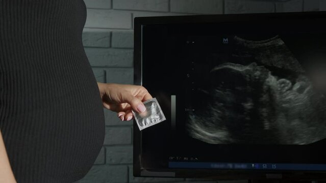 Condom contraception at pregnant female. A view of female with pregnant belly hold a condom contraception.