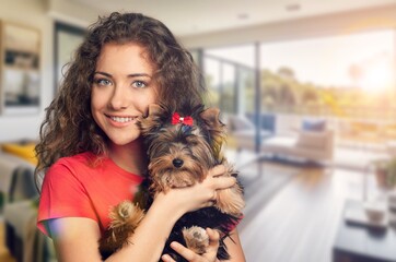 a girl holds cute domestic dog in room background