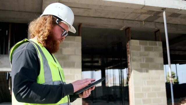 Supervisor man analyzing work at construction site, builder engineer holding digital technologies tablet computer checking data.