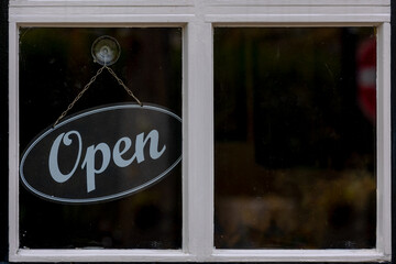 Black wooden sign with word "Open" hanging in front of entrance door, Glass window of Restaurants, Cafe' or Shops, Welcome board for customers or guests, Business and financial background.