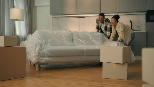 Happy satisfied couple home owners moving in new house relocation African American family move couch buy furniture sofa delivery woman man in love affection hugging real estate mortgage bank credit