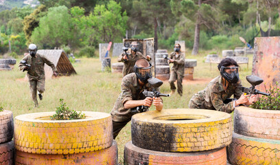 Couple of paintball players in camouflage, european man and woman in masks, playing paintboll...