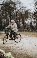 Fototapeta premium Mature female retiree cycling outdoors, embracing an active lifestyle and leisure time in nature.