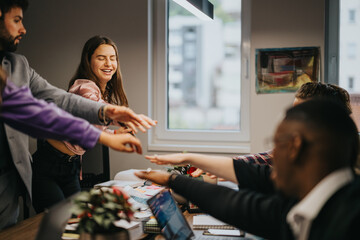 A diverse group of professionals joyously engaging in a high five during a collaborative meeting in a modern office setting.