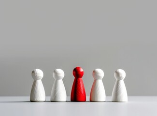 White wooden people standing on the table, among them there is one red person who stands out from all others.