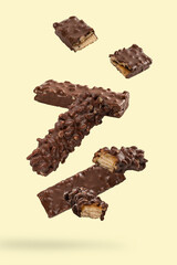Falling chocolate bar with nuts on light yellow background.