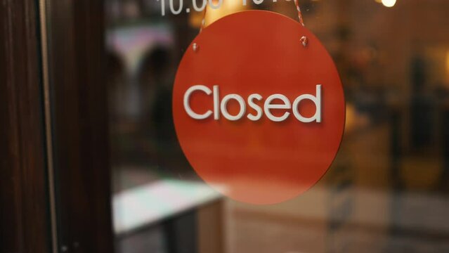 An Amber circle sign with peach logo hangs on a glass door