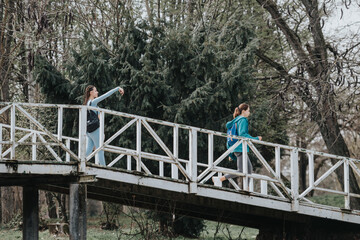 Two female athletes stretching on a white bridge surrounded by trees, focusing on their fitness routine in a natural park setting.