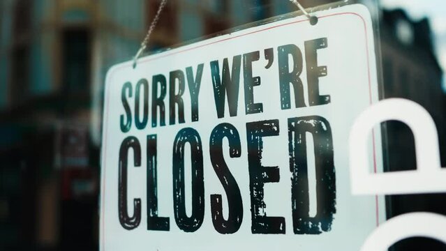 a sign that says sorry we re closed is hanging in a window