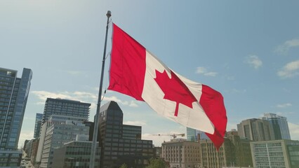 The drone hovers above downtown Halifax, capturing the majestic sight of a large Canadian flag fluttering proudly in the wind. 