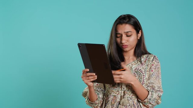 Woman trying to do purchases, frustrated with error received while adding payment method on website, studio background. Upset person unable to do internet shopping, getting card rejected, camera A