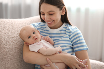 Mother with her cute baby in armchair at home