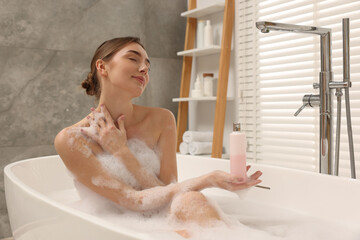 Woman taking bath with shower gel in bathroom