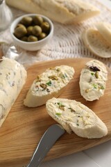 Tasty butter with olives, green onion, bread and knife on table