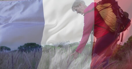 Fototapeta premium Image of flag of france over happy caucasian woman walking at field