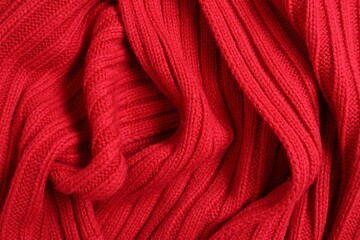 Red knitted scarf as background, top view