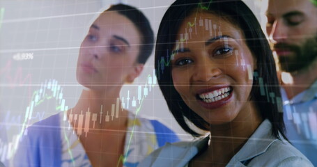 Image of graphs moving over biracial smiling businesswoman with coworkers in office