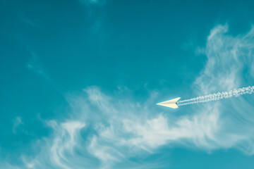 Fototapeta premium Paper airplane flying over a blue sky with copy space, representing freedom and journey concept, ideal wallpaper