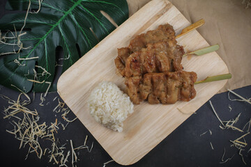 Sticky rice with grilled pork on wooden cutting board. Moo ping is grilled pork in traditional Thai...