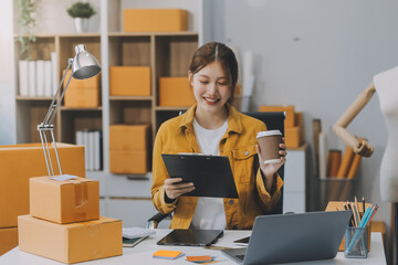 Asian SME business women use laptop computer checking customer order online shipping boxes at home....