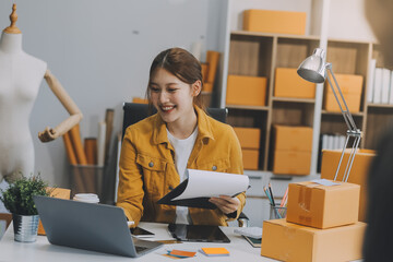 Asian SME business women use laptop computer checking customer order online shipping boxes at home. Starting Small business entrepreneur SME freelance. Online business, Work at home concept.